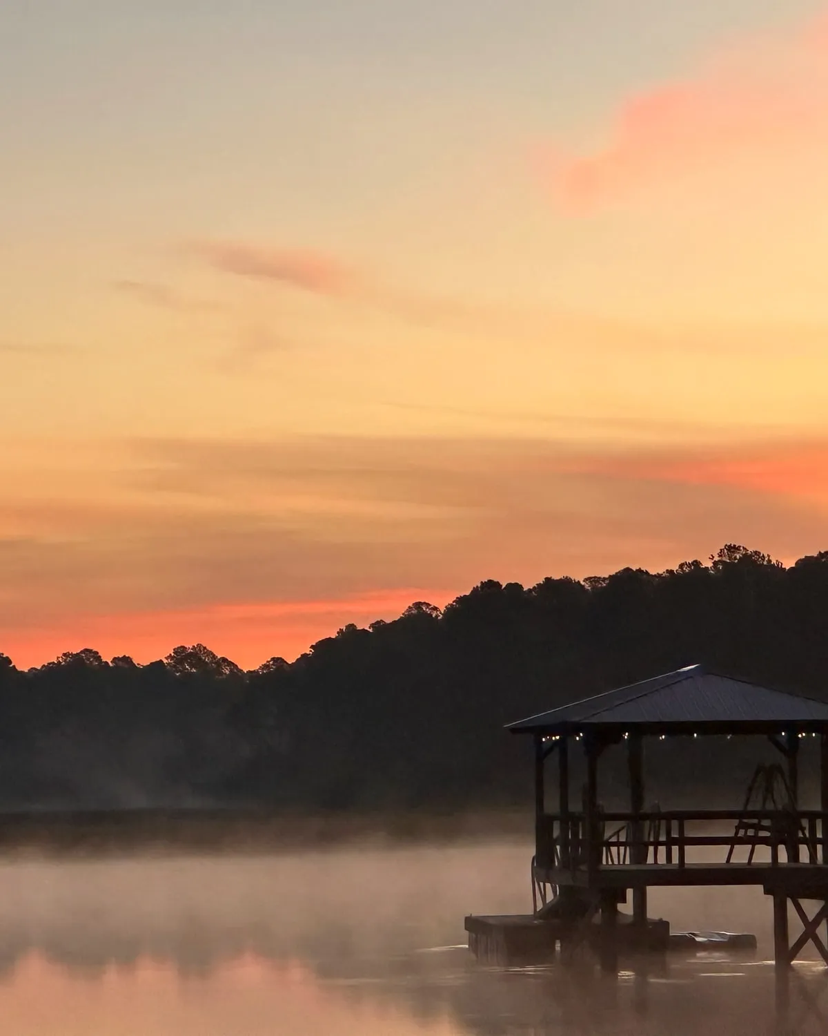 Dawn light over a Georgia coastal marsh, mist lying across still water with a dock at the edge of the frame.